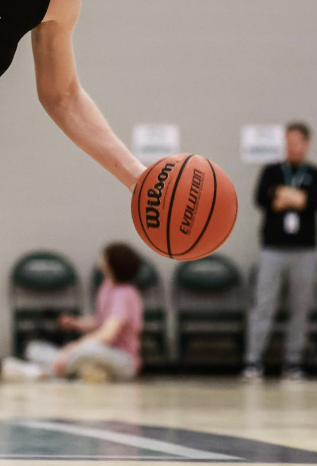 An athlete runs across a basketball court during a game with a Wilson brand basketball. This is also the brand that the National Basketball Association uses (NBA).